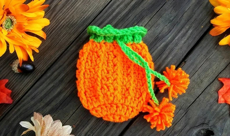 Crocheted orange pumpkin party favor bag with green drawstring stem