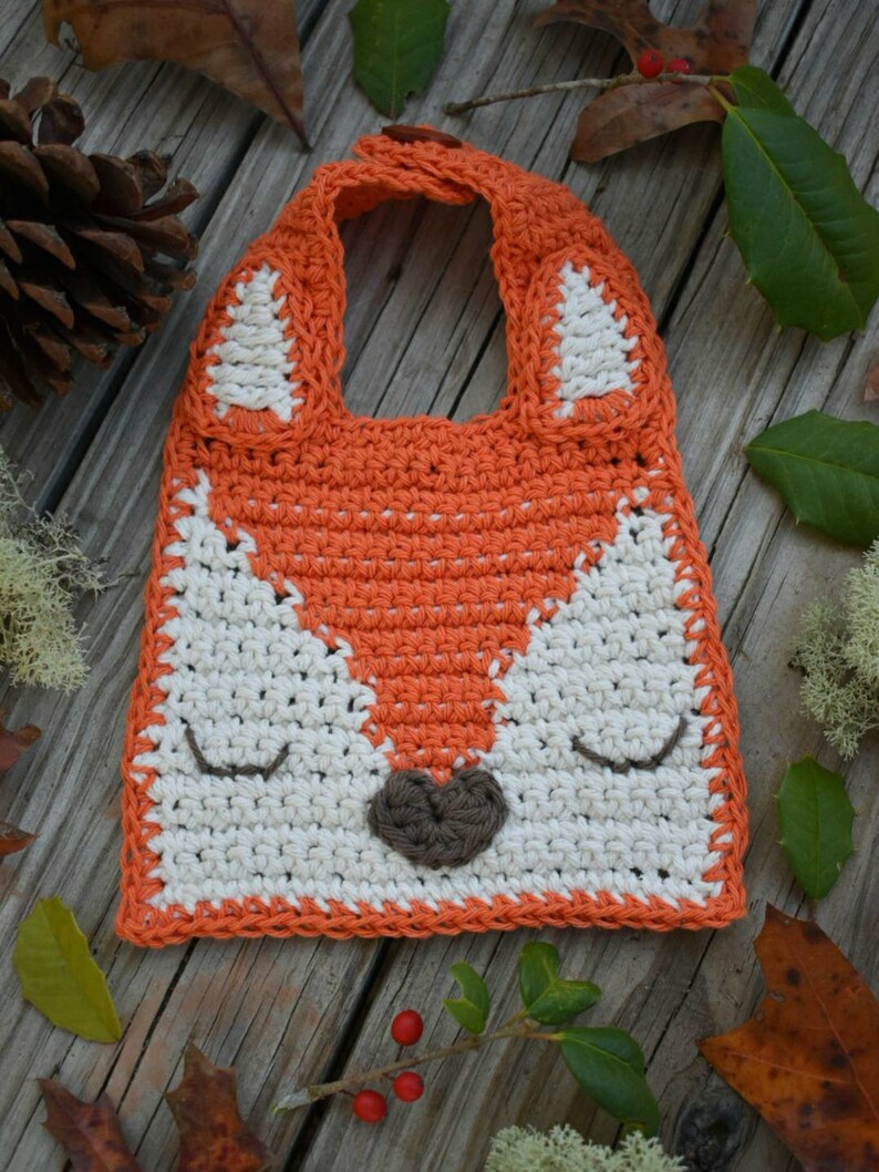 Crocheted woodland fox baby bib in white and orange cotton yarn with fox ears and button straps