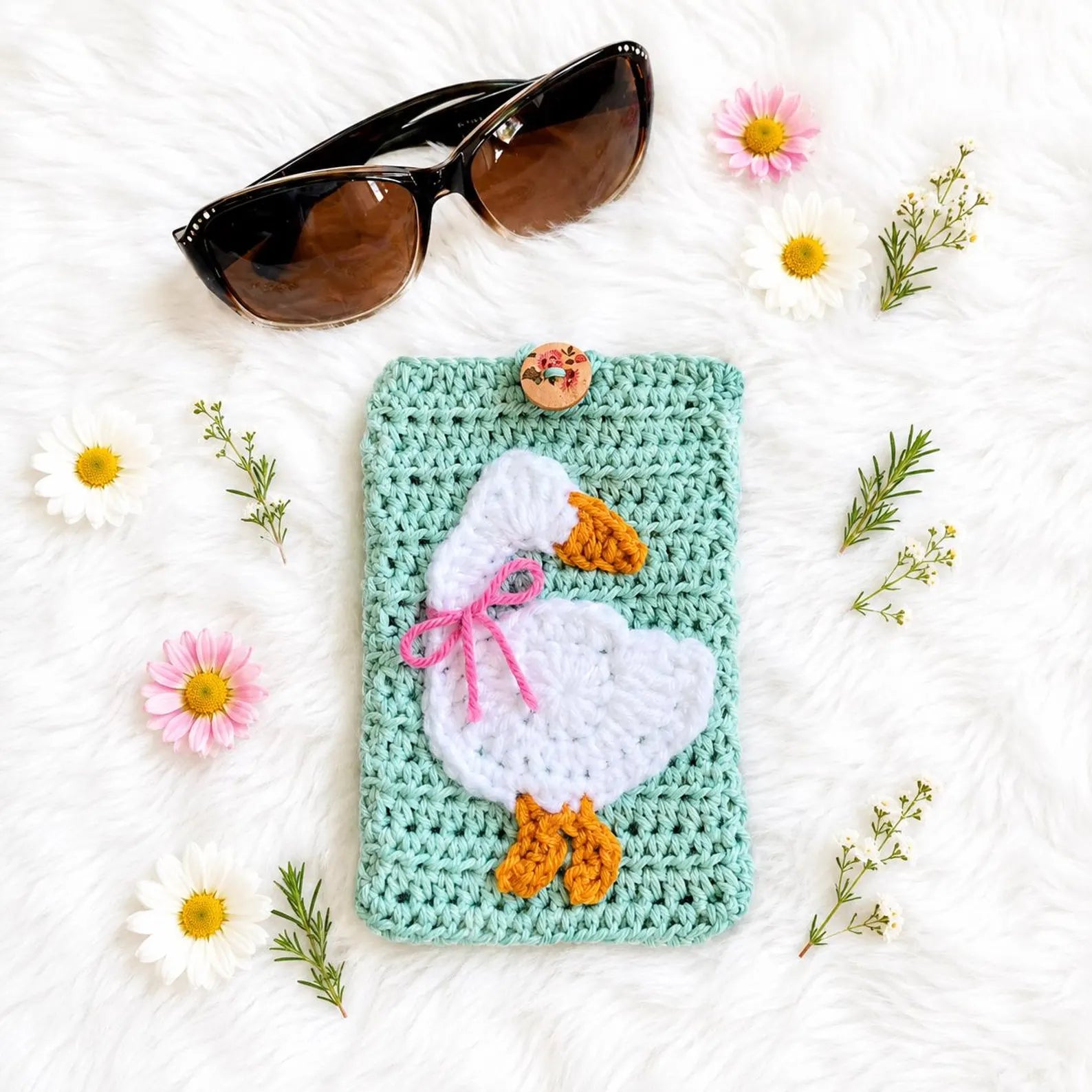 Teal crochet square appliqued with a white goose, blue bow, and yellow feet
